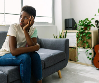 A Black Woman Sitting On A Couch Wondering What Are The Risks With Abortion.