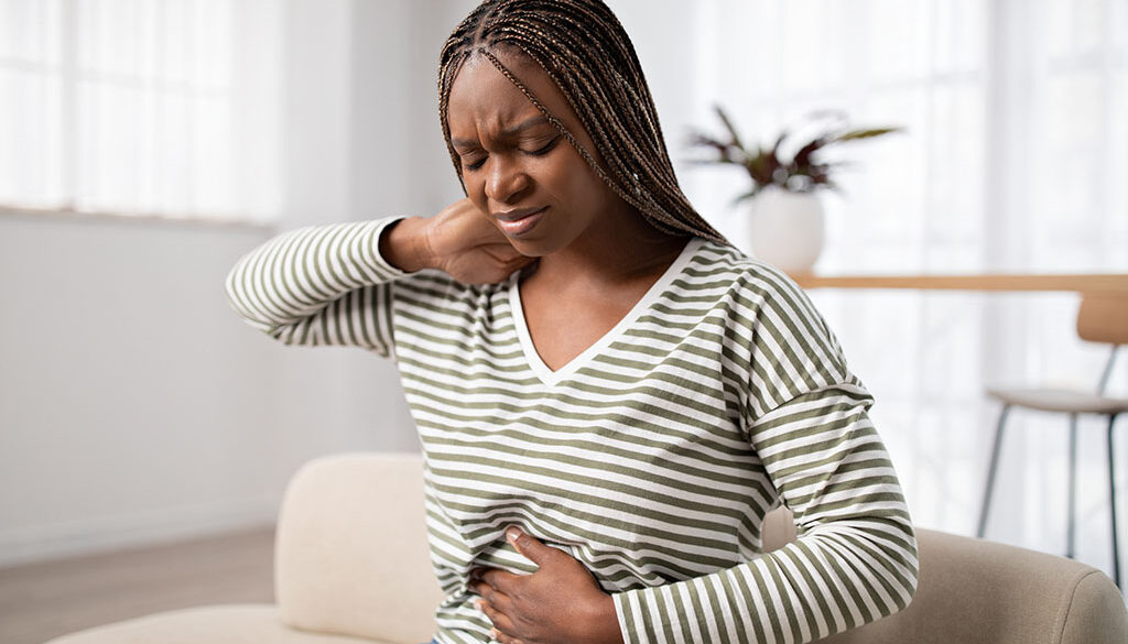 A Black Woman Holding Her Stomach Experiencing Early Pregnancy Symptoms