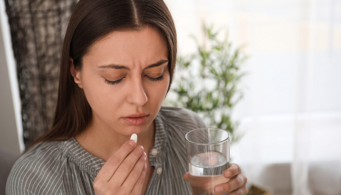 A Young Woman Visibly Upset While Holding a Glass of Water and an Abortion Pill Reversal