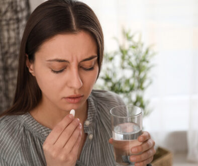 A Young Woman Visibly Upset While Holding a Glass of Water and an Abortion Pill Reversal